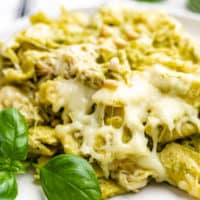 Close up view of crockpot chicken pesto pasta on a stack of plates.