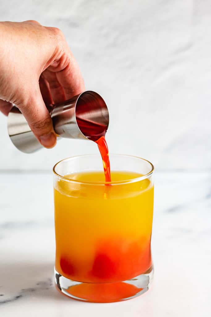 Grenadine being poured into a cocktail.