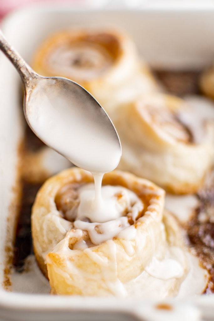 Glaze being drizzled over a cinnamon roll.