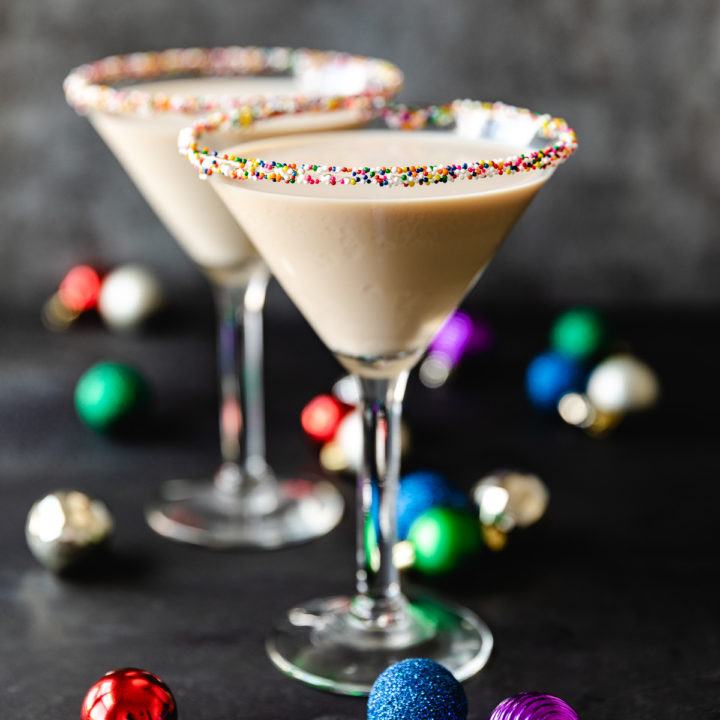 Close up view of sugar cookie martinis next to Christmas ornaments.