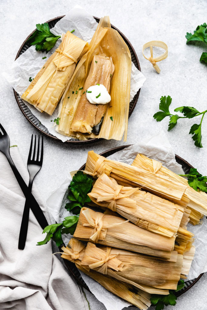 Batch of green chile and cheese tamales on plates.