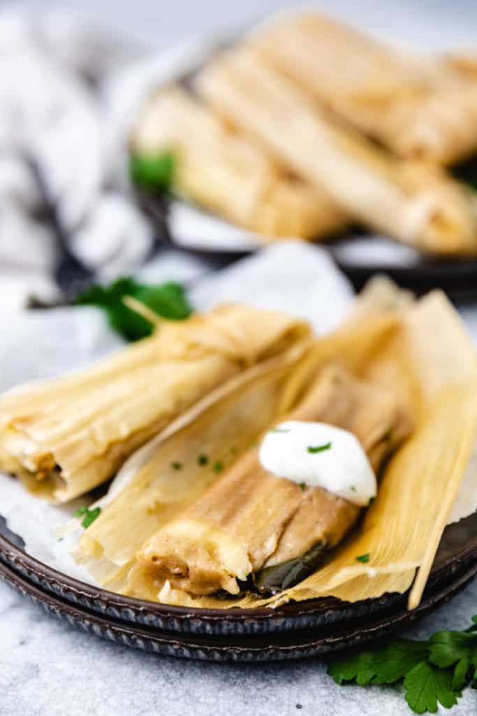 Side view of a tamale laying on a corn husk.