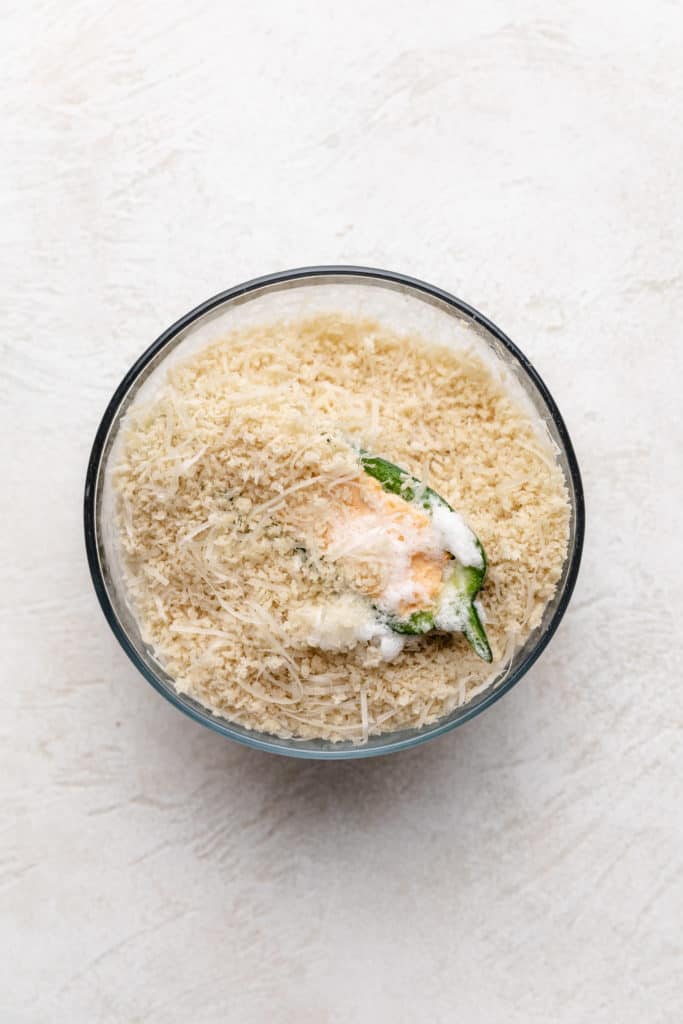 Cream cheese jalapeño in a bowl of breadcrumbs.