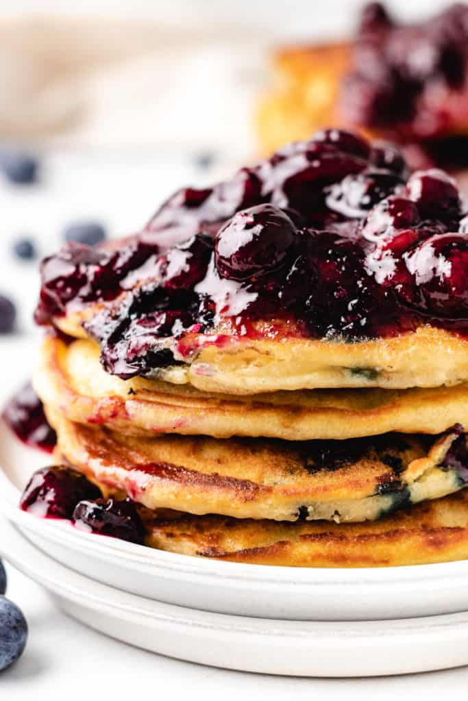 Close up view of a stack of blueberry pancakes with compote.