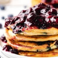 Side view of a stack of pancakes with blueberries.