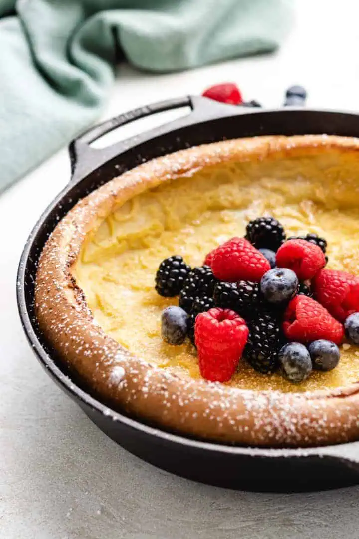 Side view of a fluffy Dutch baby pancake in a metal pan.