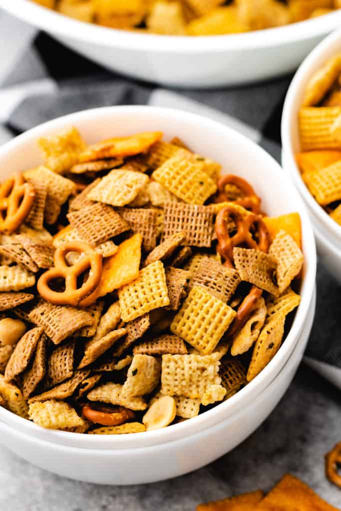 Side view of spicy chex mix in a set of white bowls.