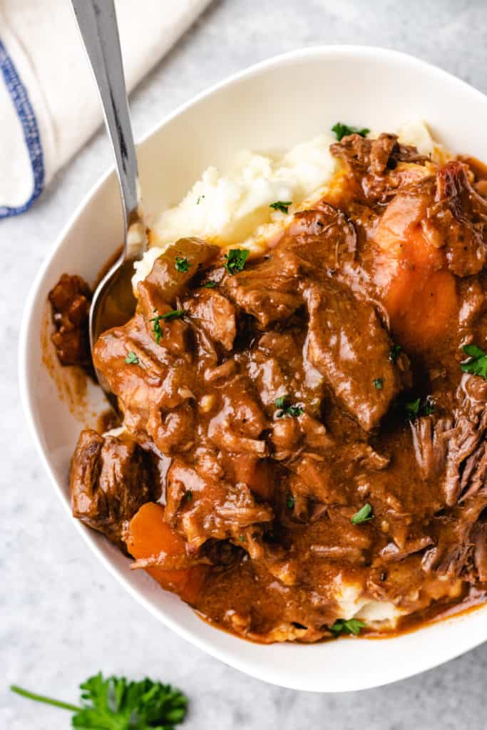 Close up view of stew with Guinness over mashed potatoes.