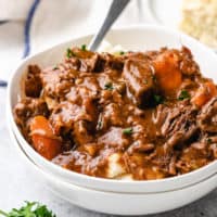 Side view of white bowls filled with mashed potatoes and irish beef stew.