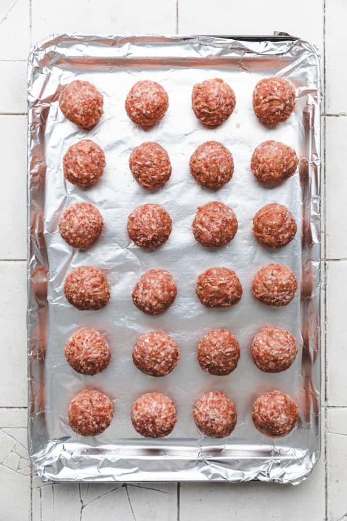 Unbaked meatballs on a baking sheet.