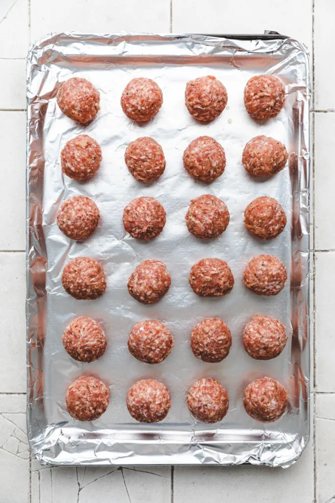 Unbaked meatballs on a baking sheet.