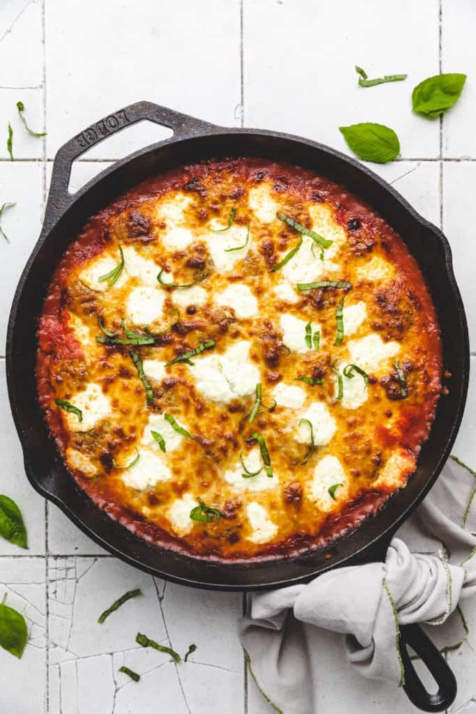 Close up view of a pan of meatballs and marinara with cheese.