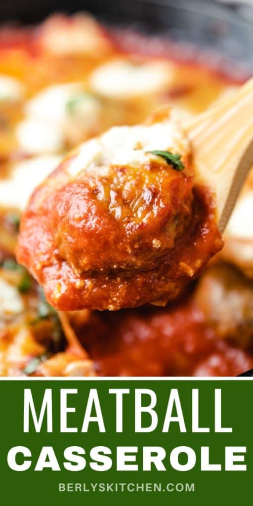 Close up view of a wooden spoon scooping up meatball casserole.