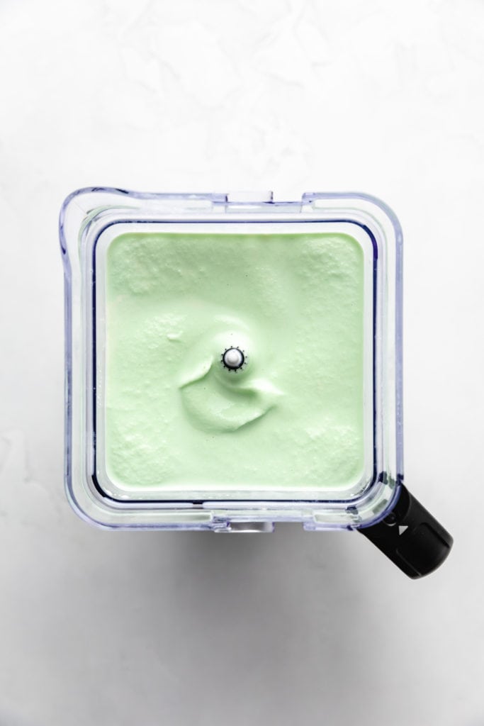 Top down view of a green milkshake in a blender.