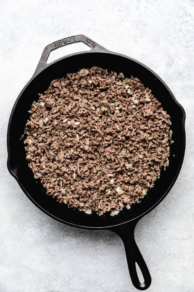 Ground beef and onion in a skillet.