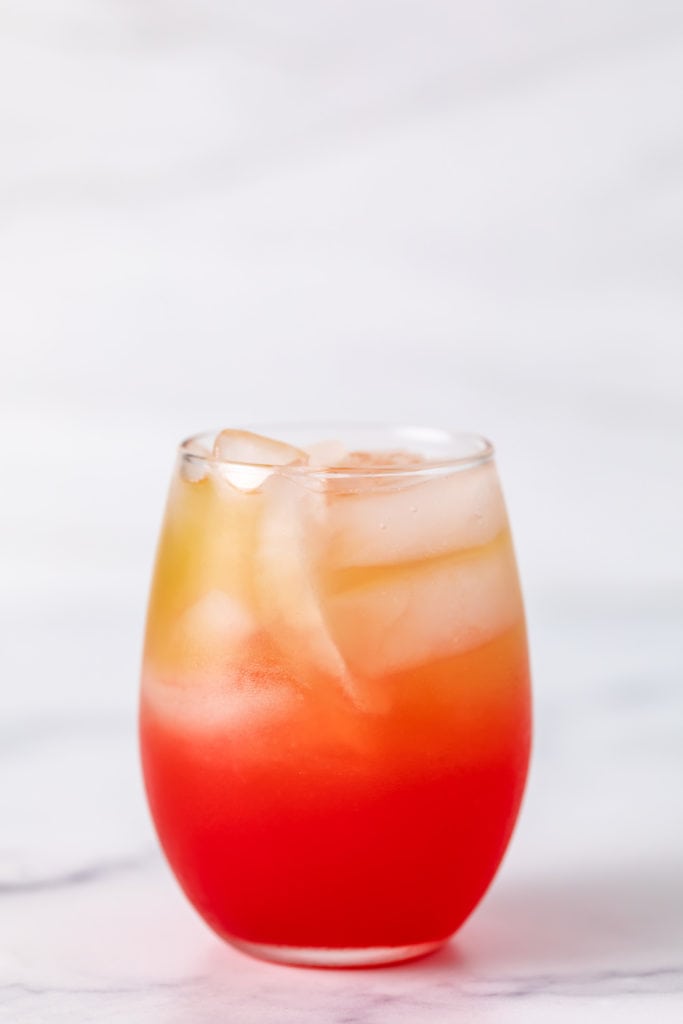 Grenadine poured into a glass of pineapple and rum.