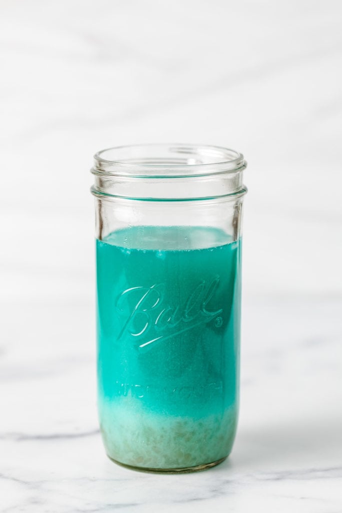Blue curacao, pineapple juice, coconut rum, and coconut cream in a jar.