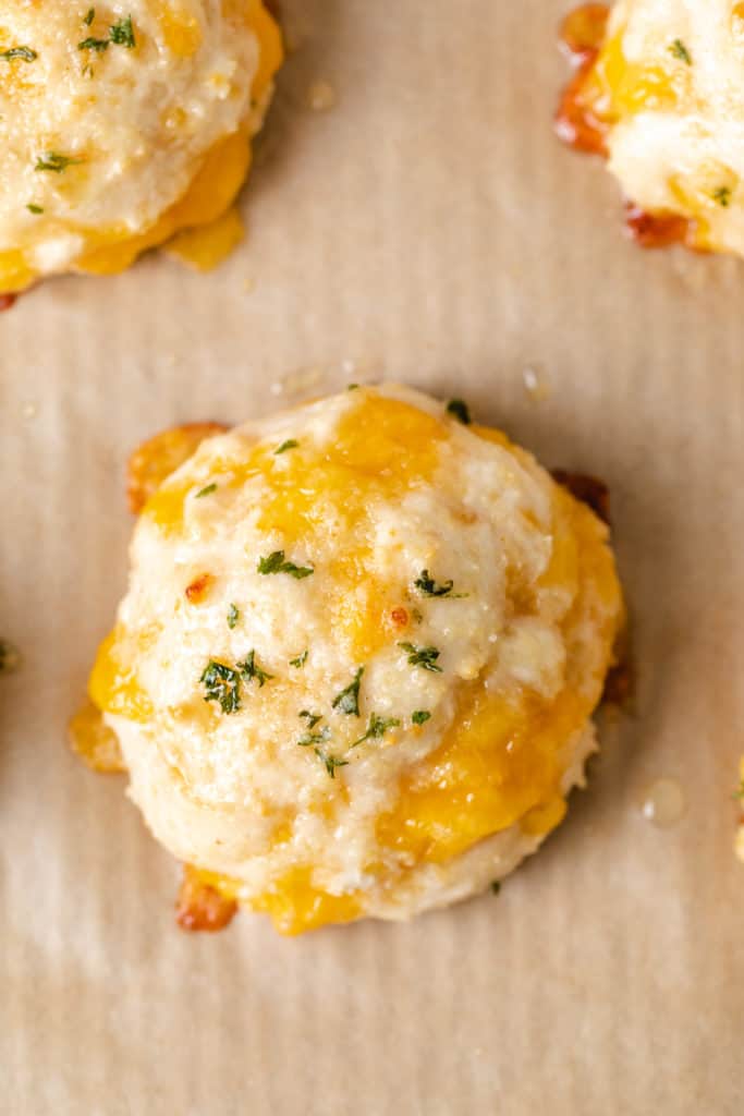 Top down view of a cheddar bay biscuit on parchment paper.