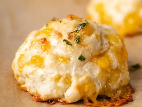 Close up view of a cheddar bay biscuit on brown parchment paper.