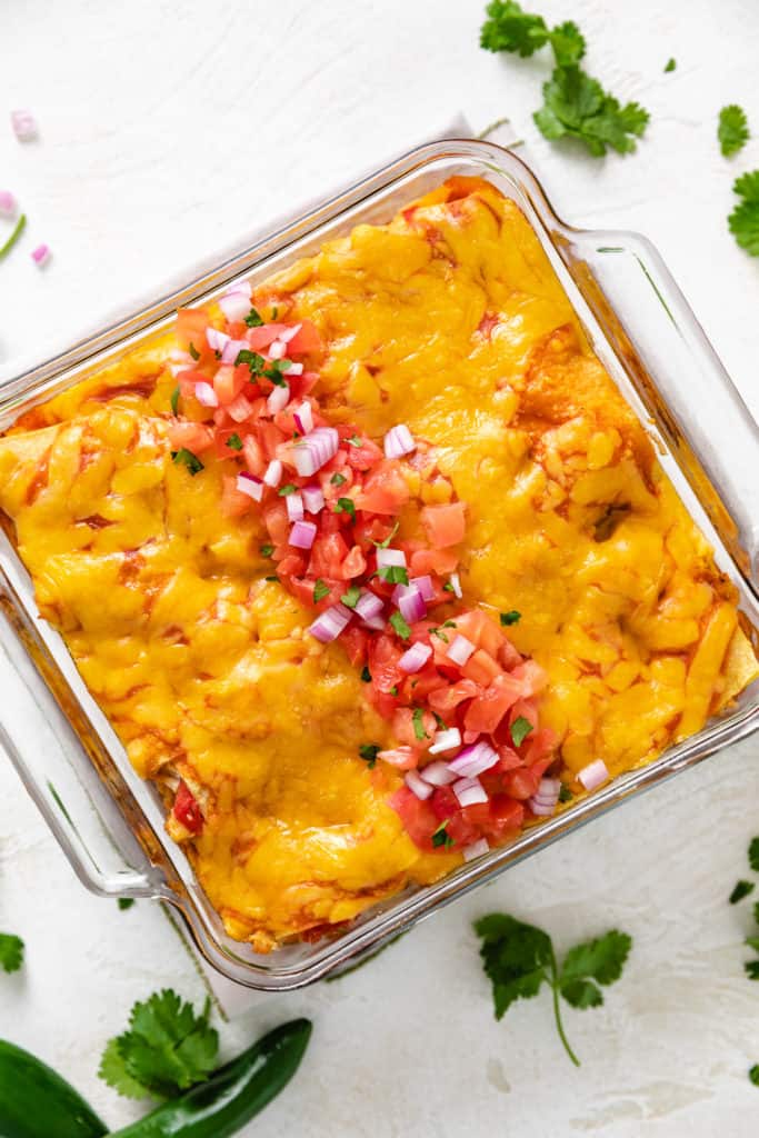 Top down view of chicken, cheese, and corn tortillas in a glass dish.