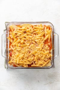 Shredded cheese added to an enchilada casserole.