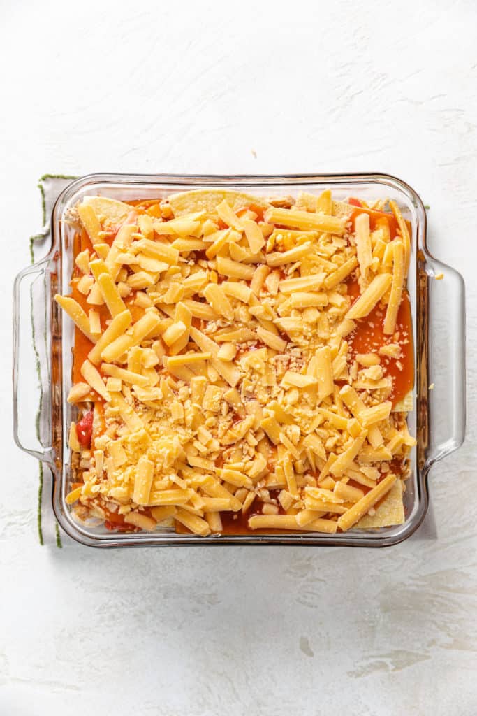 Shredded cheese added to an enchilada casserole.