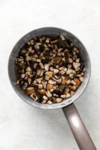 Mushrooms, broth and spices in a saucepan.