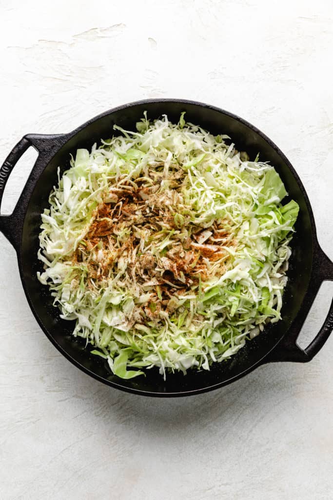 Shredded cabbage and seasonings in a pan.