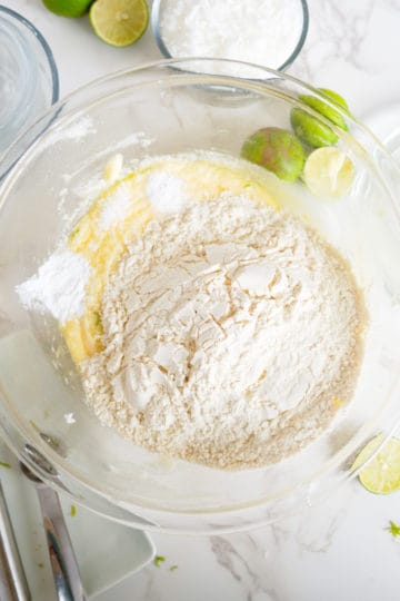 Flour added to a bowl of butter, sugar and eggs.