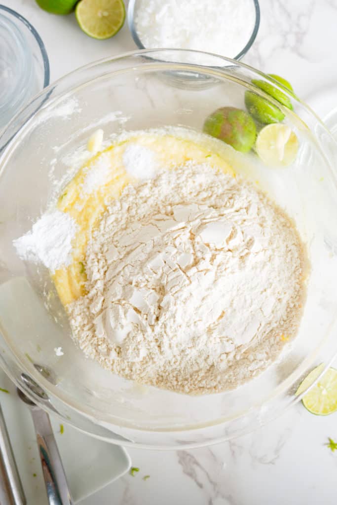 Flour added to a bowl of butter, sugar and eggs.