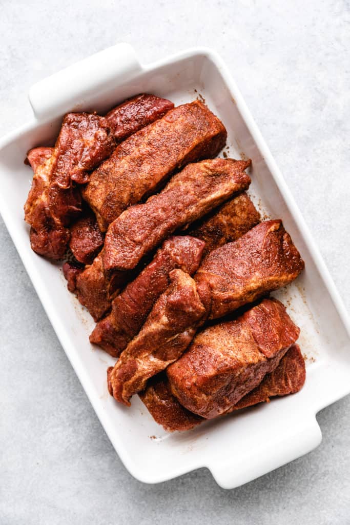 Seasoned uncooked country style ribs in a dish.
