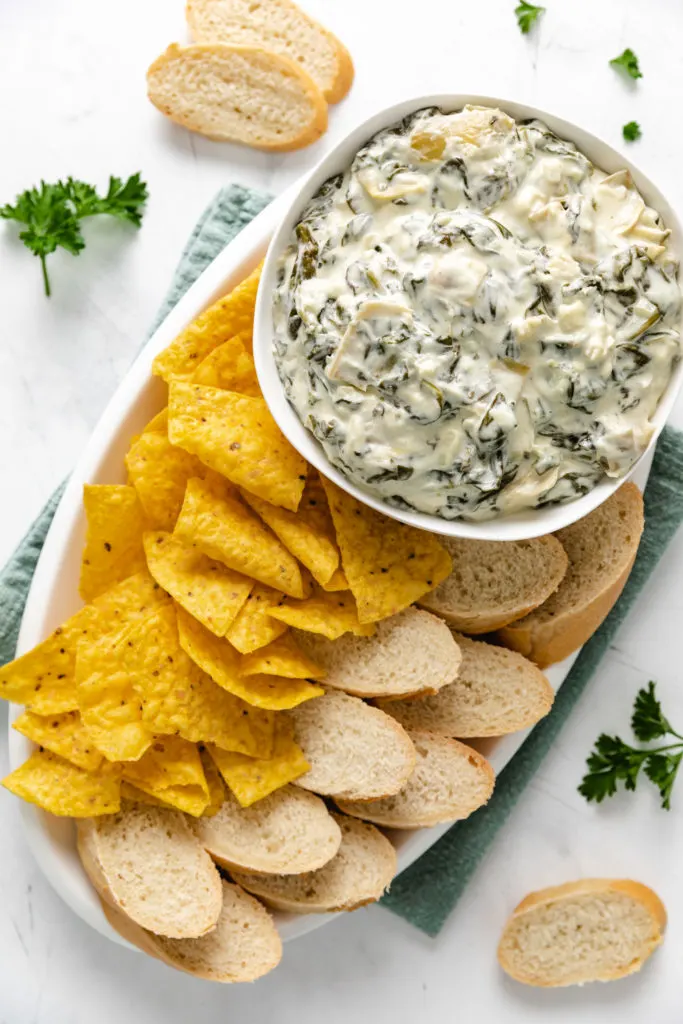 Bread, chips, and spinach dip on a platter.