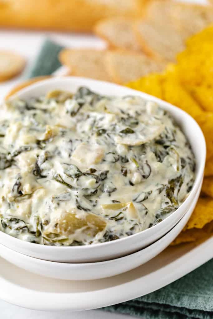 Side view of a bowl of slow cooker spinach artichoke dip.