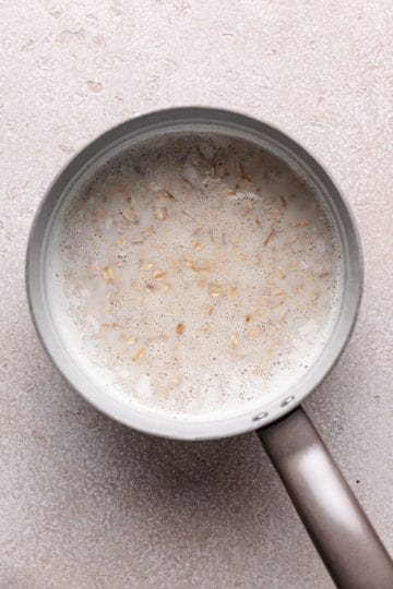 Oats poured into a pan of milk and water.
