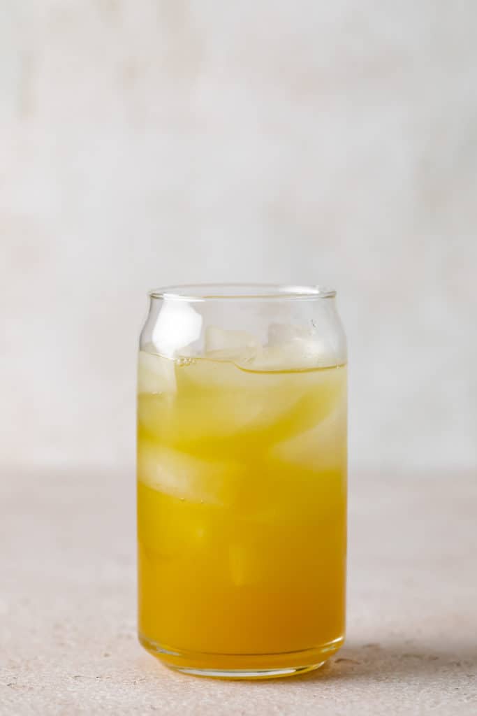 Side view of pineapple juice and coconut rum in a can glass.