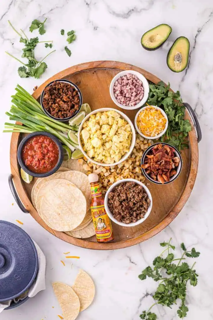 Hot sauce and potatoes added to a breakfast taco board.