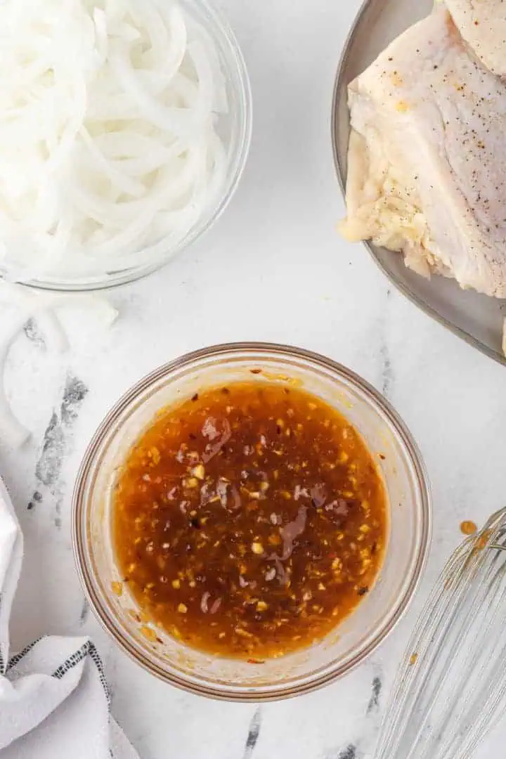 Apricot preserves, soy sauce, mustard, garlic, ginger and crushed red pepper flakes mixed in a bowl.