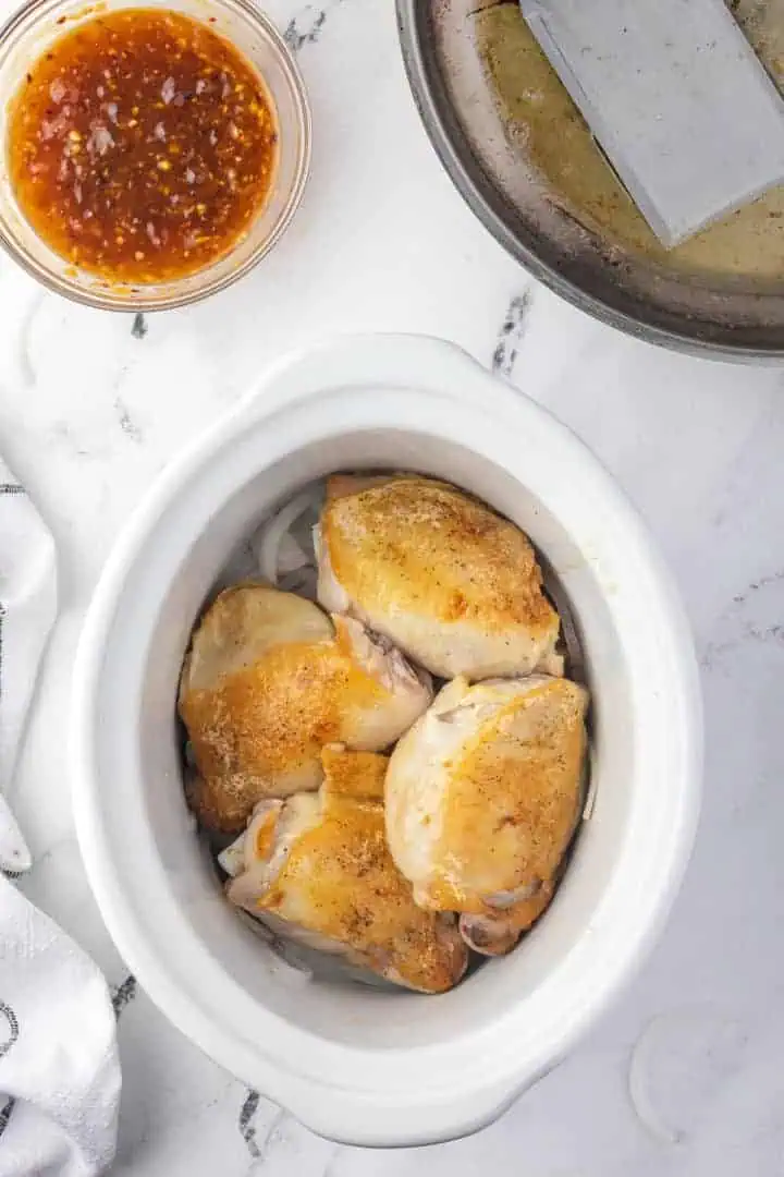 Chicken thighs and onions in a crockpot.