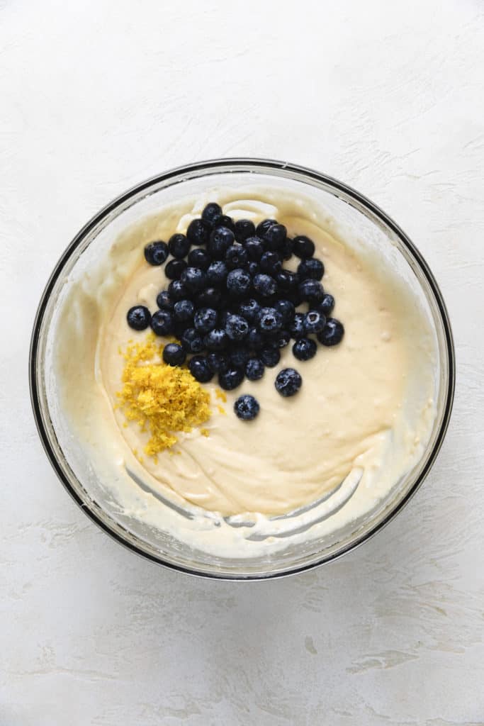 Blueberries and lemon zest on top of muffin batter.