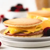 Side view of a pancake breakfast sandwich with fruit.