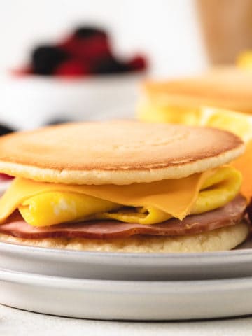Side view of a pancake breakfast sandwich with fruit.