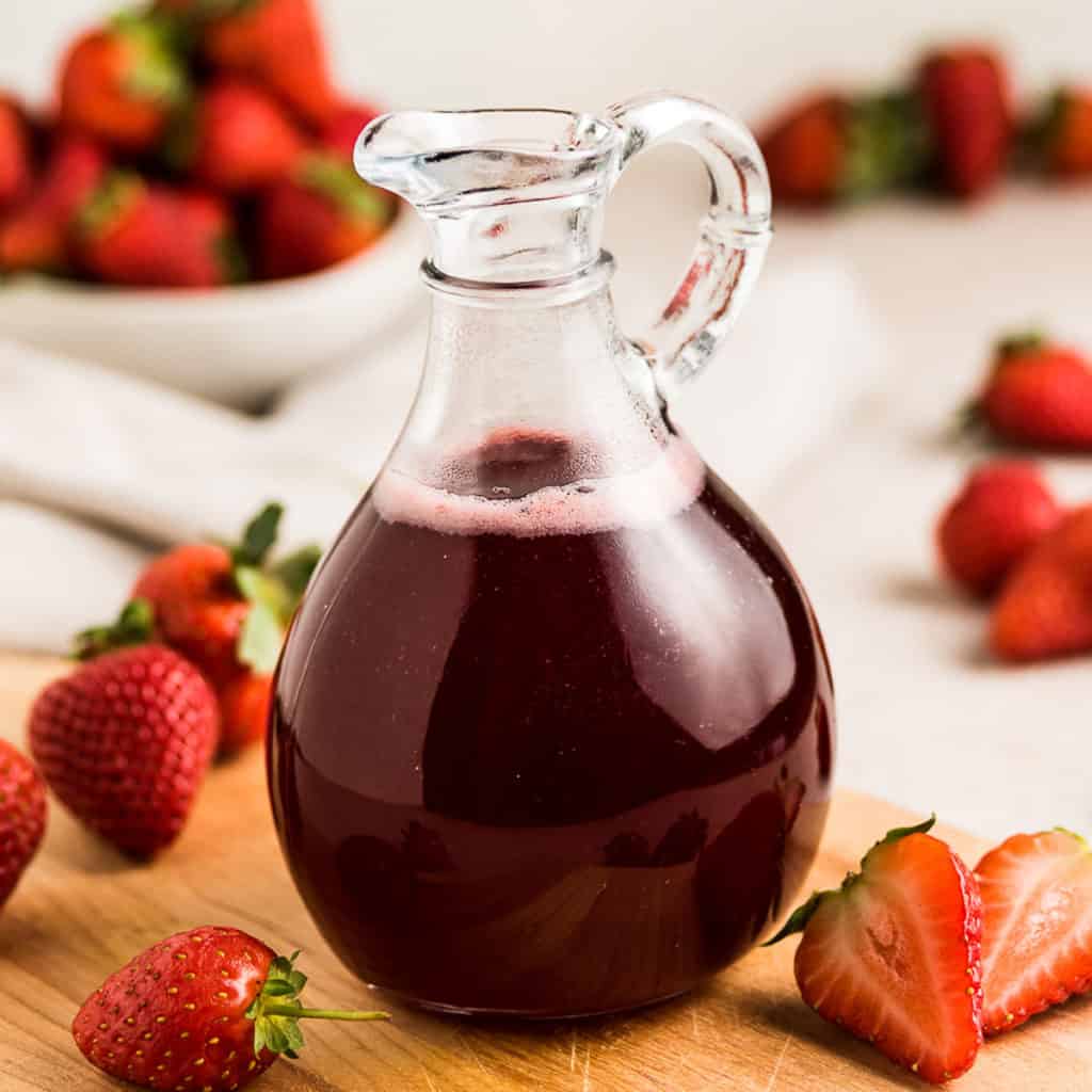 Fresh strawberries around strawberry simple syrup.