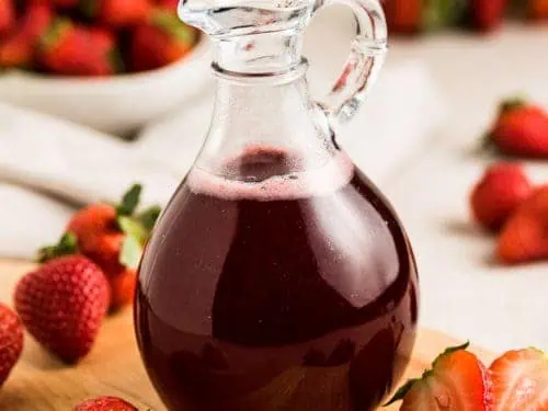 Fresh strawberries around strawberry simple syrup.