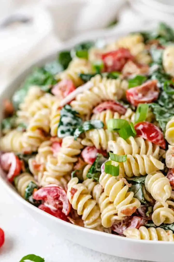 Close up view of pasta salad with bacon in a large bowl.