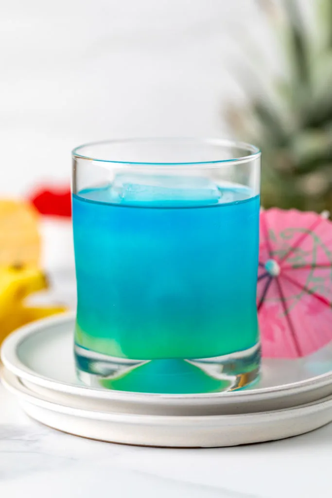 Blue curacao, pineapple juice, rum, and soda in a glass.