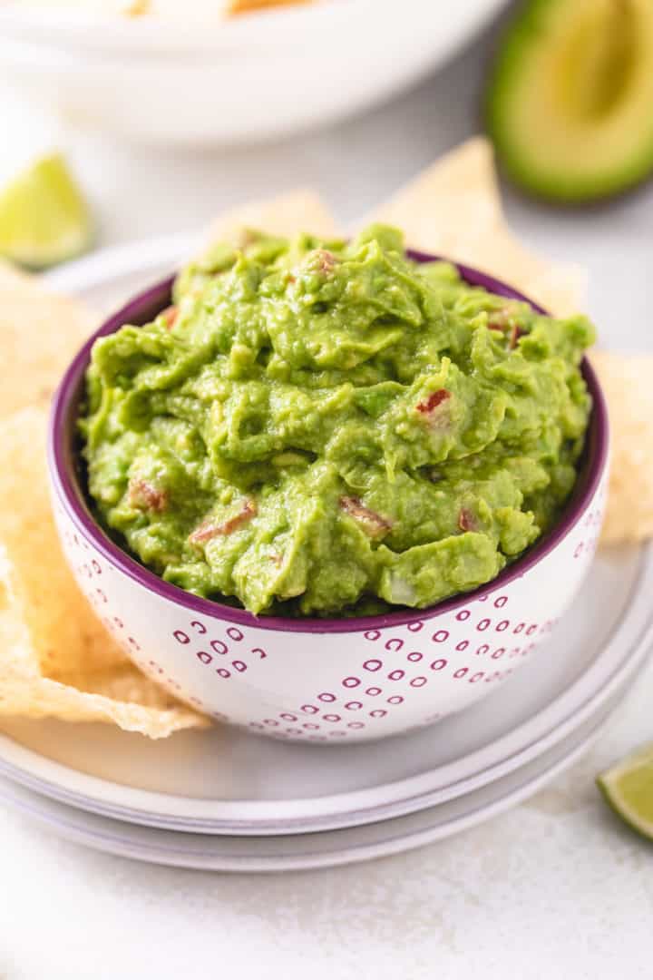 Close up view of avocado dip with tomatoes and onions in a bowl.