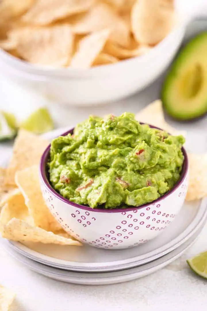 Purple and white bowl filled with freshly made guacamole.