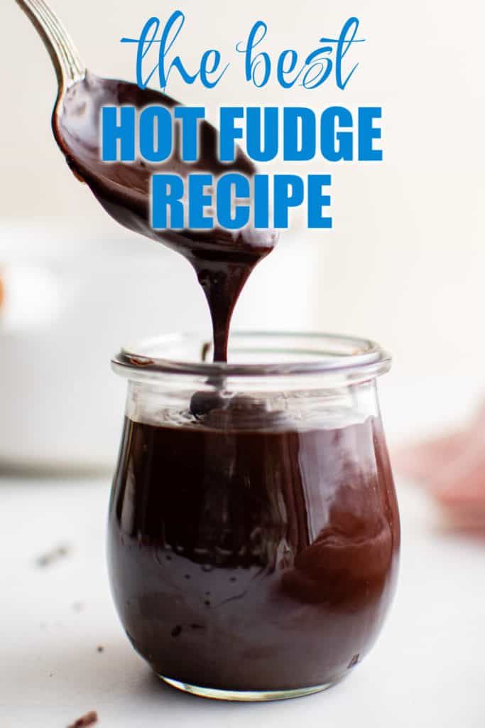 Spoon holding chocolate sauce over a jar.