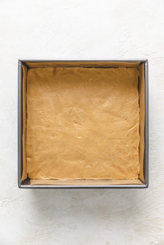 Peanut butter fudge pressed into a pan.