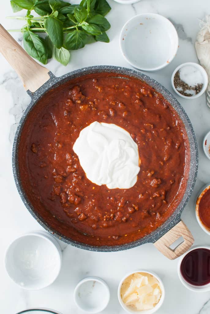 Blended cream cheese added to a pan of meat sauce.